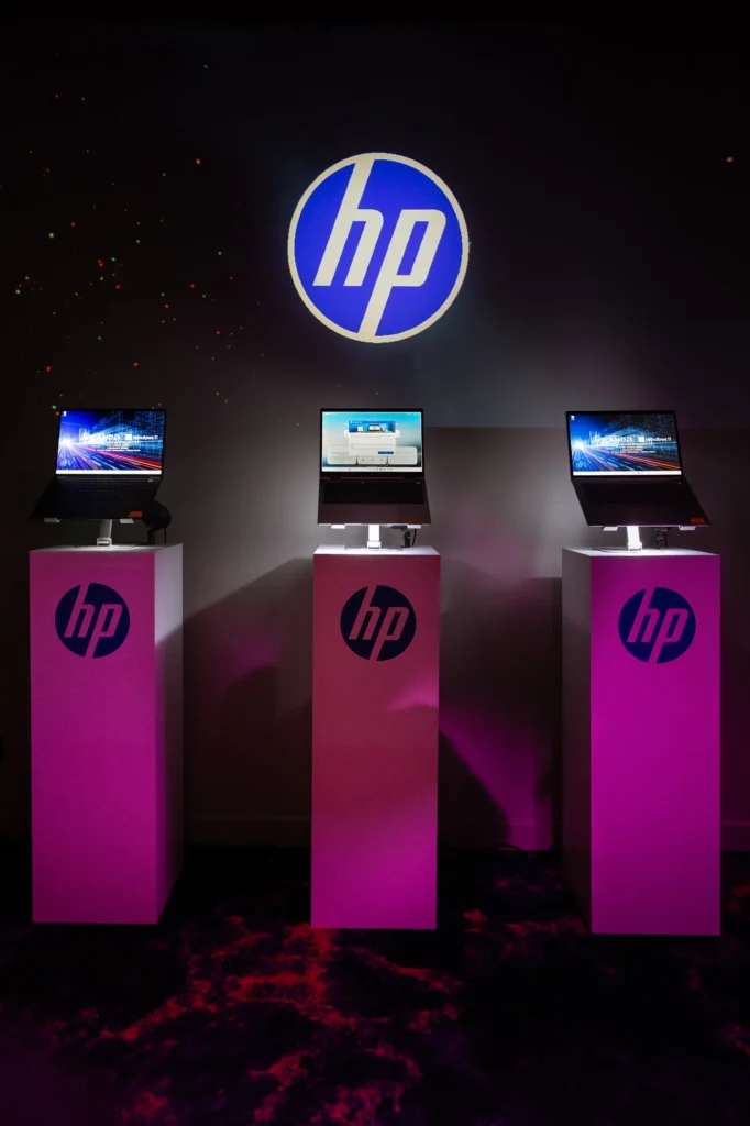 Soirée de lancement Microsoft - stands de démonstration d'ordinateurs portables HP sur colonnes roses éclairées par Event Machine