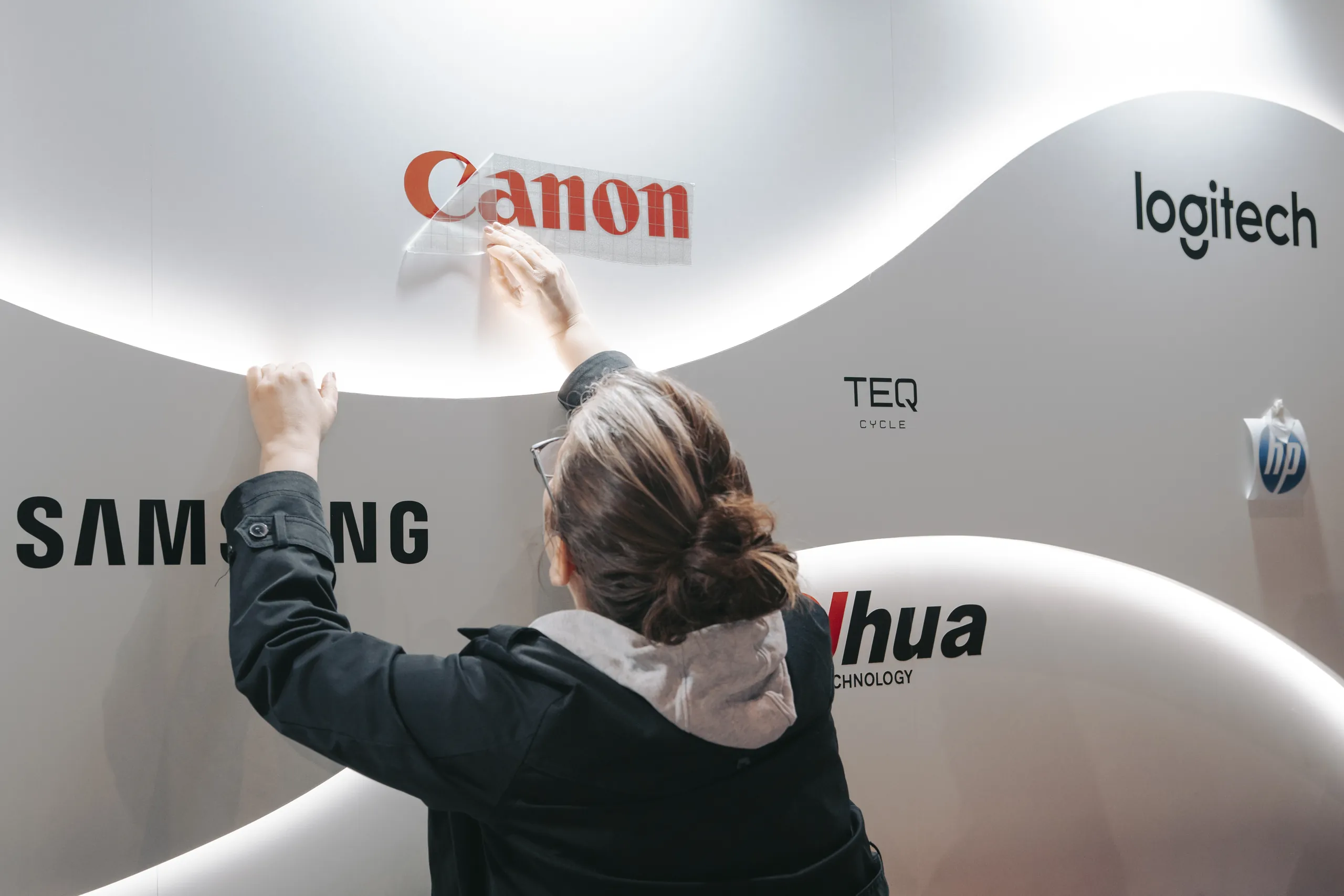 Stand ALSO - pose des logos des marques partenaires sur la cloison du stand par Event Machine